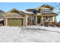 Two-story house with green and brown siding, stone accents, and a three-car garage at 581 N Flat Rock Cir, Aurora, CO 80018