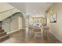 Open-concept dining area featuring sleek hardwood floors, contemporary lighting, and a modern glass-railing staircase at 2624 S Race St, Denver, CO 80210