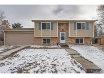 Split-level home featuring brick and siding, complemented by blue shutters and a two-car garage at 14798 E Temple Dr, Aurora, CO 80015