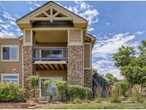 Condo exterior with stacked stone and siding, balcony, stairs, landscaping, and blue sky at 8726 S Kline St # A208, Littleton, CO 80127