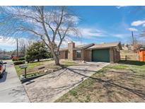 Charming brick home featuring a green garage door and a tree-lined front yard at 6779 W 79Th Cir, Arvada, CO 80003