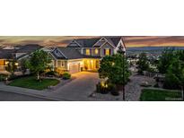 Charming two-story home with a well-manicured lawn, mature trees, and a paved driveway leading to a two-car garage at 696 Eveningsong Dr, Castle Rock, CO 80104