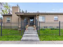 Charming brick home featuring a cozy front porch, flower pots, and secure iron fence at 1090 E 3Rd Ave, Denver, CO 80218