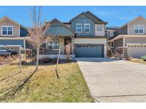 Beautiful two-story home featuring blue and gray siding, a covered porch, and a two-car garage at 15818 E Otero Cir, Centennial, CO 80112