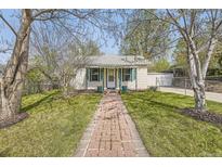 Charming home with well-manicured lawn, brick path, and cheerful green accents on the door and shutters at 5510 S Windermere St, Littleton, CO 80120