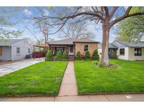 Charming brick home with a well-manicured lawn, mature tree, and welcoming front porch at 2989 S Corona St, Englewood, CO 80113