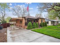 Charming brick home featuring a well-manicured lawn, covered carport, and an inviting front porch at 2989 S Corona St, Englewood, CO 80113