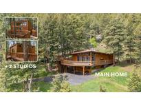 Scenic home with a large deck and wood accents surrounded by lush greenery and mature trees at 4923 Snowberry Ln, Evergreen, CO 80439