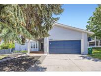 Charming light blue home featuring a blue garage door, covered porch, and well-maintained landscaping at 10890 Stuart Ct, Westminster, CO 80031