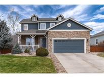 Beautiful two-story home featuring a stone facade, blue siding, covered porch, and well-manicured lawn at 14669 Eagle River Run, Broomfield, CO 80023
