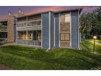Attractive two-story condominium with blue siding, stone accents, two balconies, and a lush lawn at 8600 E Alameda Ave # 21-208, Denver, CO 80247