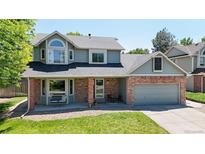 Charming two-story home with a well-manicured lawn and a cozy front porch seating area at 982 E 130Th Cir, Thornton, CO 80241