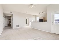 Spacious living room featuring neutral paint, plush carpeting, and access to a kitchen and entry way at 15475 Andrews Dr # 401, Denver, CO 80239