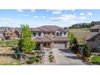 Beautiful two-story home featuring a tile roof, stone accents, a well-manicured yard and three car garage at 1240 Starglow Pl, Highlands Ranch, CO 80126
