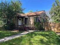 Charming brick home features a well-maintained lawn, mature trees, and a cozy front porch, perfect for relaxing outdoors at 1439 Dexter St, Denver, CO 80220