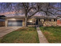 Charming brick home featuring a well-manicured lawn, attached garage, and cozy front porch at 241 S 15Th Ave, Brighton, CO 80601