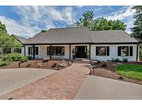 Charming single-story home with a brick pathway, lush landscaping, and black-trimmed windows at 17 E Belleview Ln, Greenwood Village, CO 80121