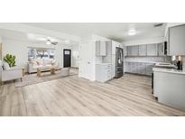 Bright, open-concept living room featuring a modern kitchen and hardwood floors at 8307 E Lehigh Dr, Denver, CO 80237