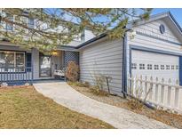 Charming home featuring light gray siding with blue trim, a covered porch, and an attached two-car garage at 7729 Beverly Blvd, Castle Pines, CO 80108