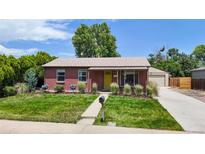 Charming brick home with a well-maintained lawn, lush landscaping, and a detached garage at 1741 W 55Th Pl, Denver, CO 80221