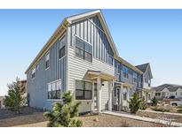 Attractive townhome exterior with blue and beige siding, complemented by neatly landscaped front yard at 7885 Yampa River Ave, Littleton, CO 80125