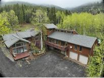 An exterior elevation showing a multi-story home with a large driveway and beautiful wooded surroundings at 2720 S Spring Gulch Rd, Idaho Springs, CO 80452