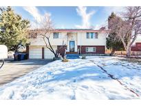 Charming two-story home featuring a two car garage and snowy front yard at 6764 Benton St, Arvada, CO 80003