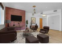 Cozy living room with a brick accent wall, modern furniture, and hardwood floors at 1438 Little Raven St # 201, Denver, CO 80202