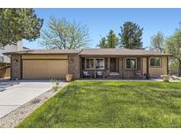 Charming brick home with a manicured lawn, inviting chairs on the front porch, and an attached two-car garage at 904 Fieldstone Pl, Highlands Ranch, CO 80126