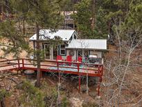 Charming exterior featuring a cozy deck with red chairs and peaceful mountain scenery at 26349 Pleasant Park Rd, Conifer, CO 80433