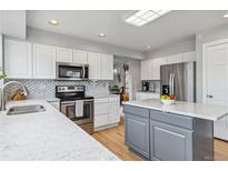 Bright kitchen features white cabinetry, stainless steel appliances, and marble countertops at 12551 W 84Th Cir, Arvada, CO 80005