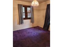 A cozy bedroom features vibrant purple carpeting and a window dressed with light gray curtains at 3036 W Clyde Pl, Denver, CO 80211