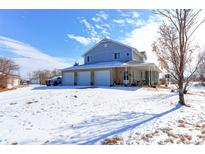 Charming two-story home with a three-car garage, inviting front porch and snow-covered yard at 409 N Garden Ct, Platteville, CO 80651