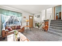 Inviting living room with a large window, a plush sofa, and an open staircase to the second floor at 16505 E Arkansas Ave, Aurora, CO 80017