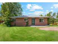 Charming brick home featuring a well-manicured front lawn and mature trees at 1060 Saulsbury St, Lakewood, CO 80214