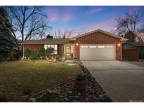 Charming brick home featuring manicured lawn, mature trees, and an attached two-car garage at 10916 W 66Th Ave, Arvada, CO 80004