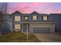 Charming two-story home with gray siding, blue shutters, brick accents and well-manicured lawn at 9837 Foxhill Cir, Highlands Ranch, CO 80129