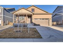 Charming home with a well-manicured lawn, inviting porch, and convenient attached two-car garage at 222 Fox St, Bennett, CO 80102