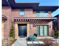 Inviting two-story brick home featuring a pergola covered entrance, professional landscaping, and a walkway to the front door at 318 Adams St, Denver, CO 80206