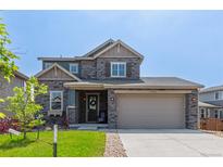 Beautiful two-story home featuring stone accents, a two car garage, and a well-maintained lawn at 9350 Dunraven St, Arvada, CO 80007