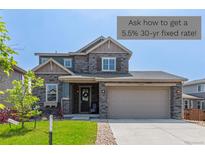 Charming two-story home featuring a stone facade, a two-car garage, and a well-manicured lawn at 9350 Dunraven St, Arvada, CO 80007