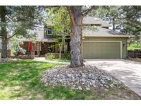 Charming two-story home with a two-car garage and lush landscaping, including a large tree at 4 Oakmont Ln, Littleton, CO 80127