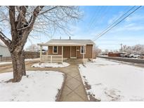 Charming single-story home featuring a cozy porch and walkway, surrounded by a snow-covered yard at 391 N 7Th Ave, Brighton, CO 80601