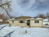 Tan house with dark door, snow covered yard at 8501 E 104Th Ave, Henderson, CO 80640