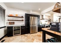 Modern kitchen featuring stainless steel appliances, black cabinets, travertine floors, and floating wood shelves at 3383 Mount Royal Dr # 46, Castle Rock, CO 80104