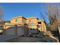 Tan two-story home with a large two car garage and a landscaped yard on a sunny day at 6584 S Sedalia St, Aurora, CO 80016