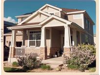 Charming two-story home with a welcoming front porch and stone accents, landscaped with flowering shrubs at 13322 Meadow Park Ln, Broomfield, CO 80020