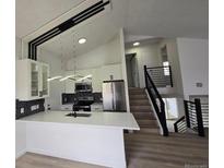 Modern kitchen with white cabinets, stainless steel appliances, breakfast bar and stylish backsplash at 17605 E Temple Dr, Aurora, CO 80015