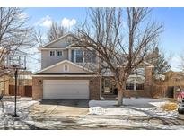 Charming two-story home featuring a brick facade, well-manicured lawn, and attached two-car garage at 13277 Elizabeth St, Thornton, CO 80241