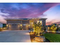Stunning exterior view of a modern home with a three-car garage, stone accents, and professional landscaping at dusk at 4213 Hickory Oaks St, Castle Rock, CO 80104